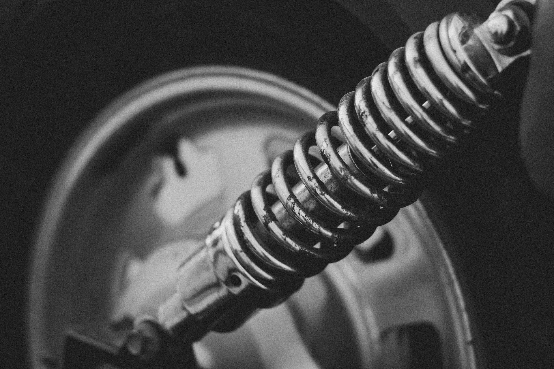 Detailed grayscale image of a vehicle suspension spring, highlighting its intricate design.