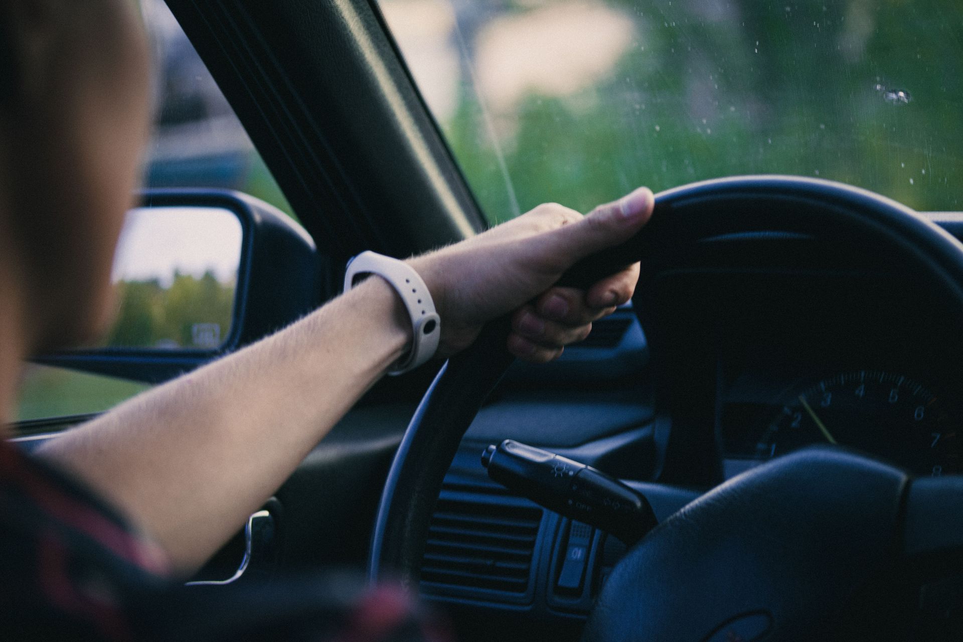 Driver's hand on steering wheel with wristwatch, focusing on control and concentration.