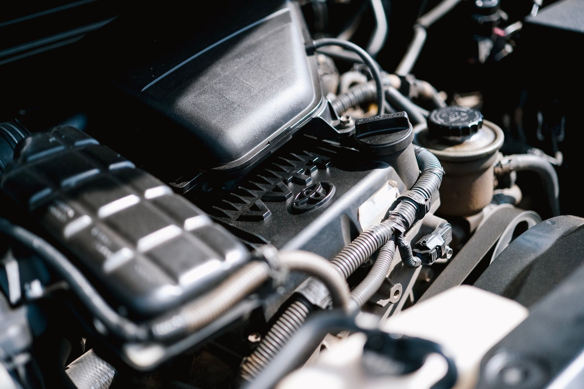 Detailed view of car engine parts, showcasing cables and components with bright lighting.