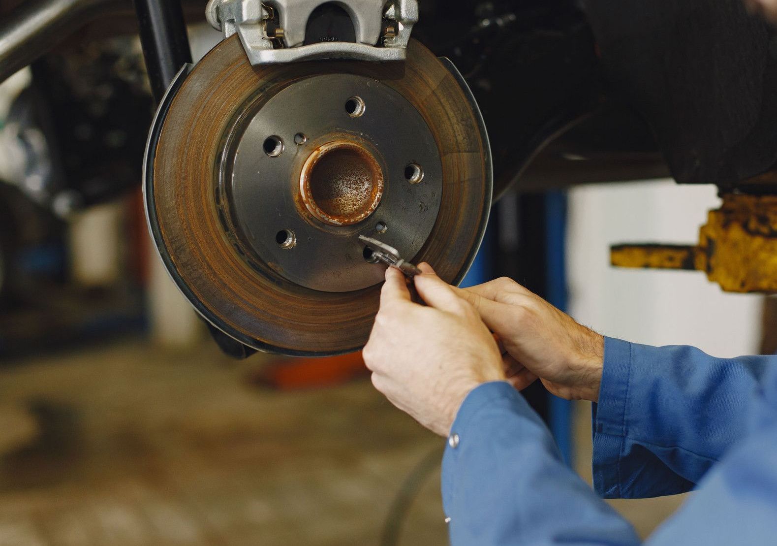 Mechanic working on brake disc in an auto repair workshop, close-up, focus on hands.